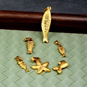 Détail macro de divers pendentifs en acier inoxydable doré, formes de poissons et étoile