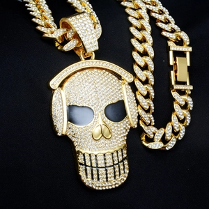 Macro shot of iced-out gold skull with headphones pendant on a cuban link chain