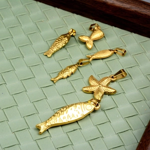 Pendentifs océaniques en acier doré poissons et étoiles de mer sur fond vert tissé