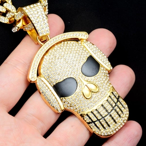 Macro shot of gold hip hop skull pendant with white crystals and black enamel eyes