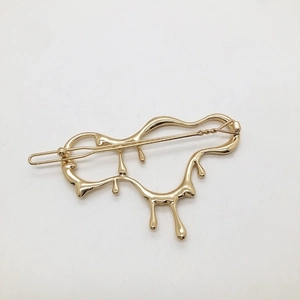 Detail of a liquid-effect gold metal hair clip with a creative lava flow design