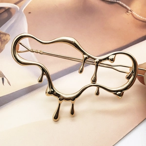 Modern fluid gold alloy hair clip with irregular molten design held in hand