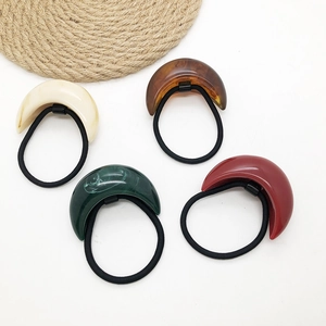 Macro detail of four vintage resin crescent hair ties in white, amber, green, and red