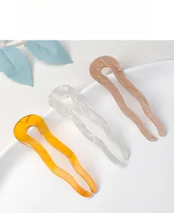 Detailed view of U-shaped wave acetate hair pins in amber, marble white, and pink