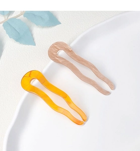 Detail view of U-shaped hair pins in amber orange and marble pink acetate material