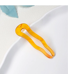 Macro detail of amber yellow wavy U-shaped acetate hair fork with marble texture