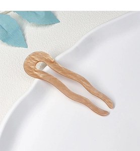 Close-up of a U-shaped wavy acetate hair pin with marble texture on white tray