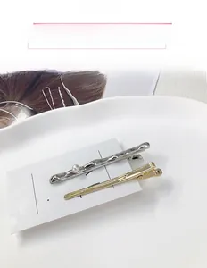 Close-up of pearl gold hair clip and wavy silver hairpin on a white display tray