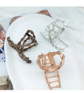 Detailed macro view of three metallic hollow woven hair claw clips in different finishes