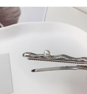 Detailed view of silver wavy metal hair clip with a lustrous white pearl accent