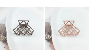 Dettaglio di fermacapelli geometrici in metallo traforato nelle finiture bronzo e oro rosa