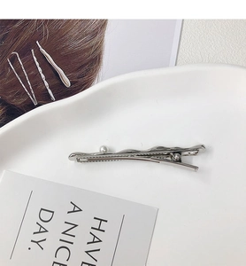 Detailed view of silver hair clip set featuring a single pearl on a polished duckbill clip