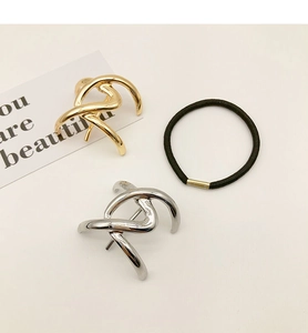 Close-up of gold and silver minimalist twisted alloy ponytail hooks with black hair tie
