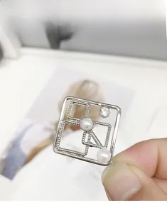 Macro shot of silver geometric hair clip with hollow squares, pearls, and zircon crystal