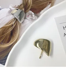 Detail showing minimalist gold and silver curved metal hair hooks with high mirror polish