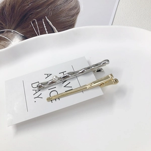 Minimalist gold and silver hair clip set with pearl accent on elegant display card