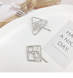 Macro shot of silver geometric hair clips with faux pearls and textured metal details