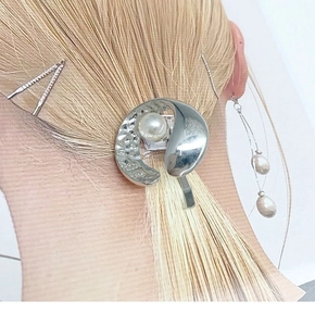 Nahaufnahme einer silbernen Haarspange mit Wirbeldesign und Perle für Pferdeschwänze