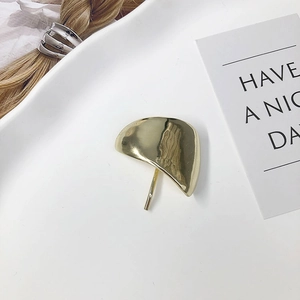 Close-up of a minimalist gold metal hair hook hairpiece on a decorative white tray