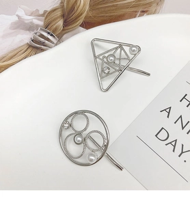 Detailed shot of silver geometric hair clips with pearls and rhinestones on white base