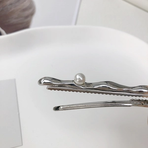 Minimalist silver wavy liquid metal hair clip featuring a white pearl and alligator grip