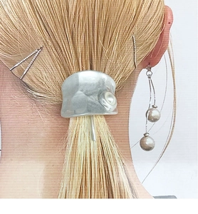 Details von silbernem Haar-Cuff mit Hammerschlag-Textur und Perle auf blondem Haar