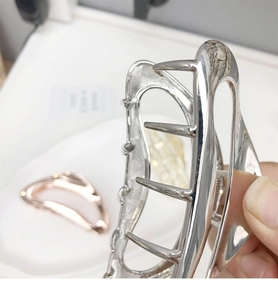 Detailed macro view of a minimalist silver metal shark hair claw clip with strong spring