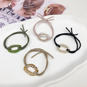 Detail of four high-elasticity hair ties with resin rings on a white ceramic plate