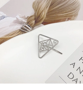 Close-up of a silver triangle hair clip with elegant pearls and sparkling rhinestones