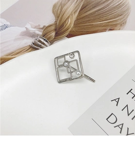 Detail of silver square hollow hair clip with double pearls and rhinestone on white background