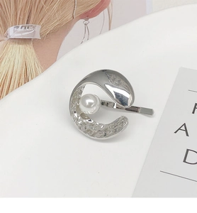 Detailaufnahme der silbernen Haarspange in Mondform mit Perle und Hammerschlag-Effekt
