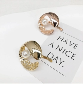 Detail of metallic C-shaped hair clips with pearls and hammer texture in gold and rose gold