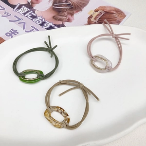 Detailed view of three elastic hair ties in green, pink and amber acetate with metal rings