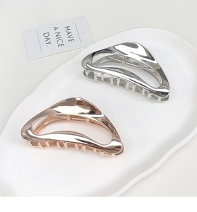 Detail of silver and rose gold metal shark hair clips on a white ceramic tray