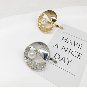 Macro detail of gold and silver pearl hair hooks with vintage hammered metal texture