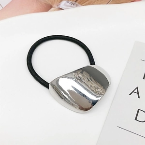 Macro view of polished silver metal geometric heart charm on black elastic hair tie