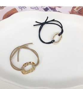Detail showing elastic hair ties with black and amber acrylic oval buckles in a white tray