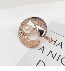 Close-up of rose gold crescent hair clip with pearl and hammered metal texture