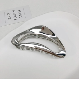 Detailed macro view of a silver metallic irregular streamlined hollow hair claw clip