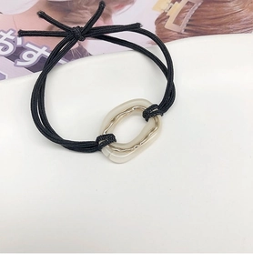Detail of minimalist black elastic hair tie with cream acrylic and gold metal buckle