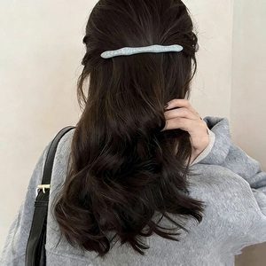 Dettaglio del fermaglio per capelli a onda azzurro con scaglie dorate su mezza coda