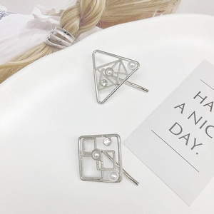 Silver geometric ponytail hooks with white imitation pearls and crystals in a ceramic dish