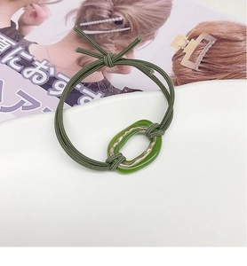 Detail of dark green hair scrunchie with oval resin ring and gold metal insert