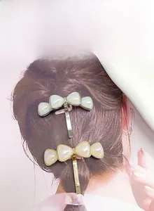 Macro view of elegant metallic bow hair hooks featuring iridescent pearl resin inlay