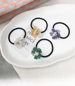 Detalle de gomas de pelo de flores de 30mm con perlas y cristales en un plato blanco