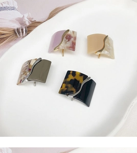 Detail of four leopard print resin hair pins in various colors on a ceramic tray