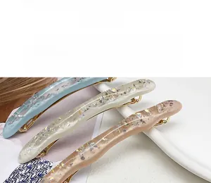 Dettaglio di fermagli per capelli ondulati in acetato azzurro e rosa con glitter oro