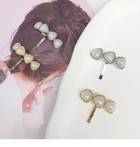 Elegant pearl heart hair clips in gold and silver finish shown on a model and tray