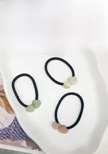 Détail d'élastiques à cheveux avec perles en forme de cœur mat et bordures dorées