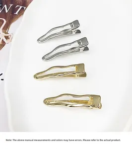 Close-up of set of four wavy metal duckbill hair clips in gold and silver finish